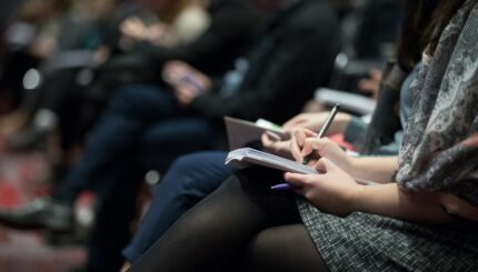 selective focus photography of people sitting on chairs while writing on notebooks